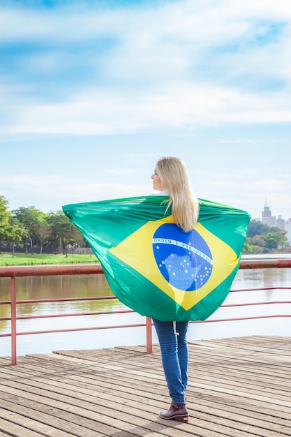 Mulher envolta em uma bandeira brasileira vestindo jeans Mulher do agronegócio