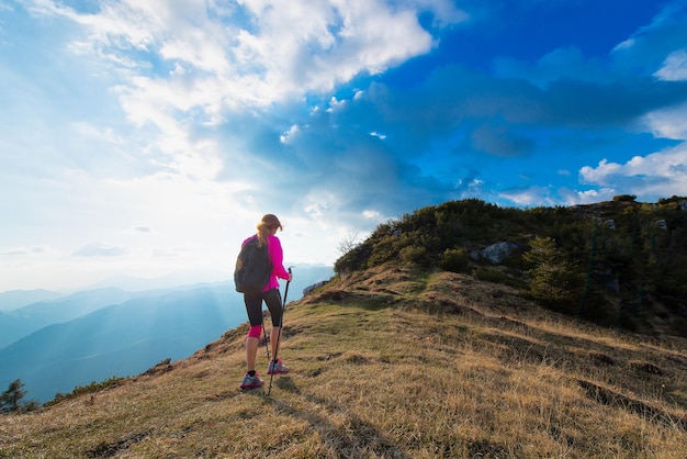 Mulher esbelta praticando caminhada nórdica nas montanhas