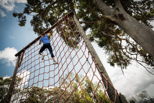 Mulher escalando uma rede durante uma pista de obstáculos
