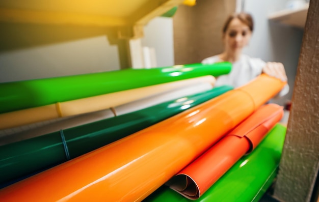 Mulher escolhe filme de vinil de cores diferentes em tubos redondos Produção publicitária Uma loja vendendo