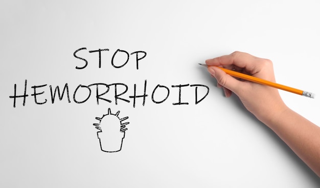 Mulher escrevendo a frase Stop Hemorrhoid na vista superior de fundo branco
