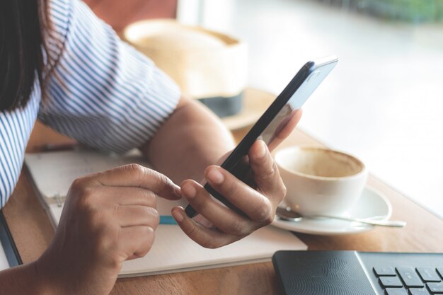 Foto mulher, escrevendo a mensagem de texto no telefone inteligente em um café.