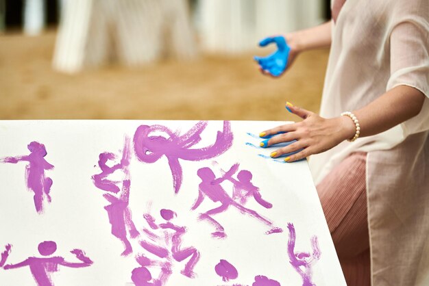 Foto mulher esfregando pintura azul em tela expressão artística em festival de arte ao ar livre pintura a gotejamento
