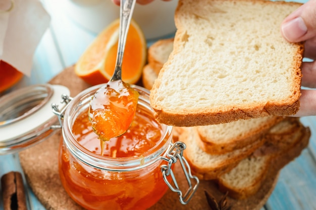 Mulher espalha fatias de pão com geléia de laranja