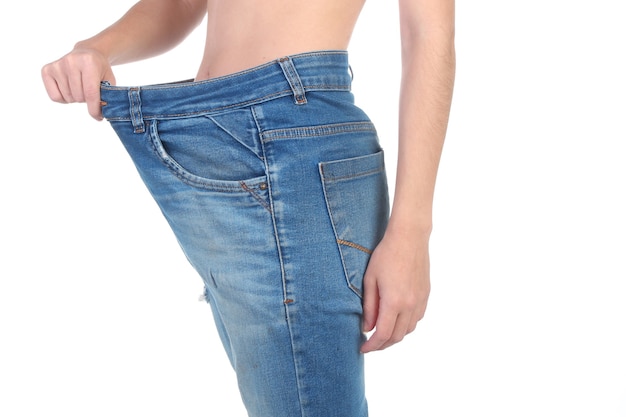 Mulher espantada a puxar calças largas, mostrando que perdeu peso