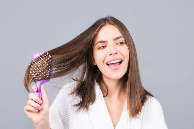 Mulher espantada, penteando o retrato do modelo feminino com um pente, escovando a garota do cabelo com escova de cabelo hai