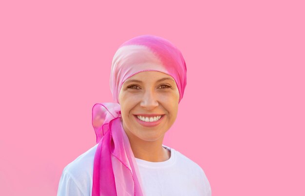 Mulher esperançosa usando um lenço na cabeça em um fundo rosa