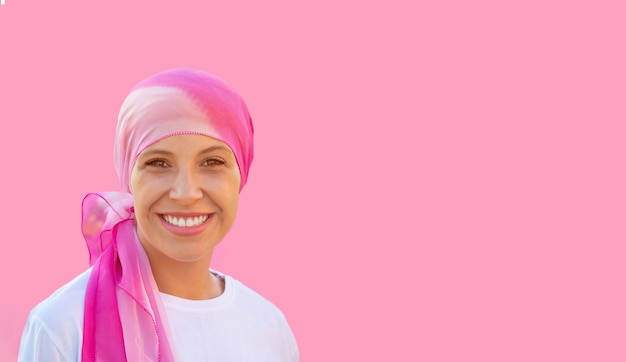 Mulher esperançosa usando um lenço na cabeça em um fundo rosa