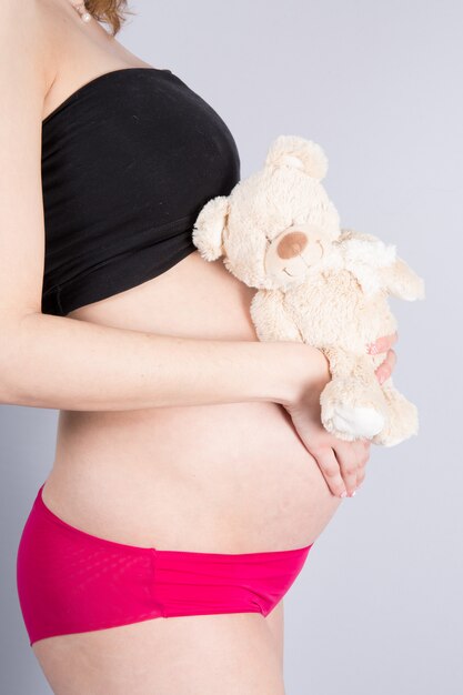 Mulher esperando um bebê com um fofo urso de pelúcia