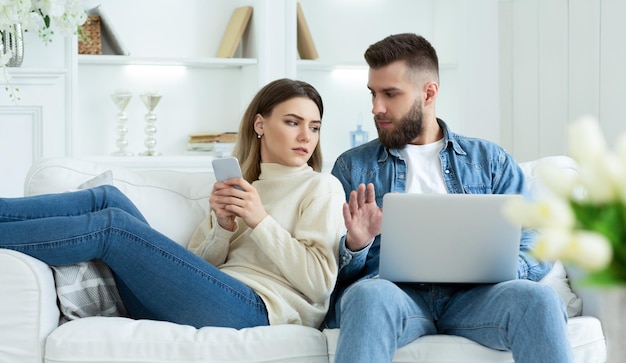 Mulher espionando o laptop do marido sentados juntos no sofá