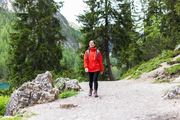 Mulher espiritualmente forte caminhando sozinha nas montanhas com capa de chuva vermelha
