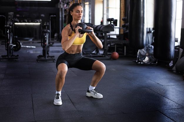 Mulher esporte com kettlebell no ginásio.