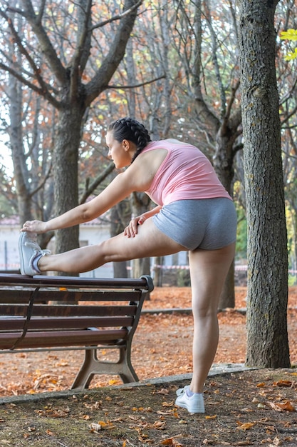Mulher esportiva atraente se aquecendo em um parque Linda garota fazendo exercícios de aquecimento em um parque