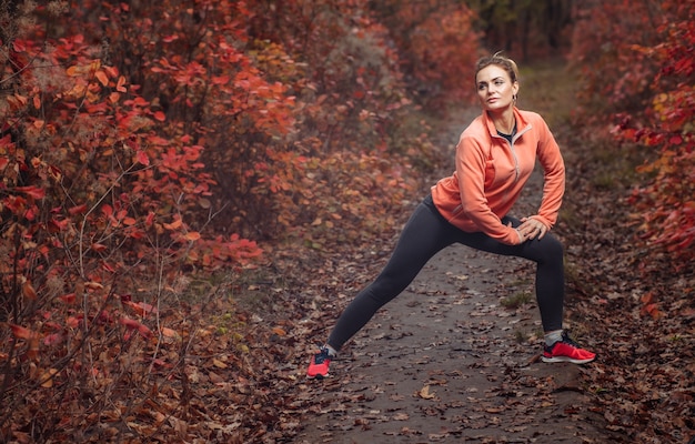 Mulher esportiva cansada em roupas esportivas na floresta de outono