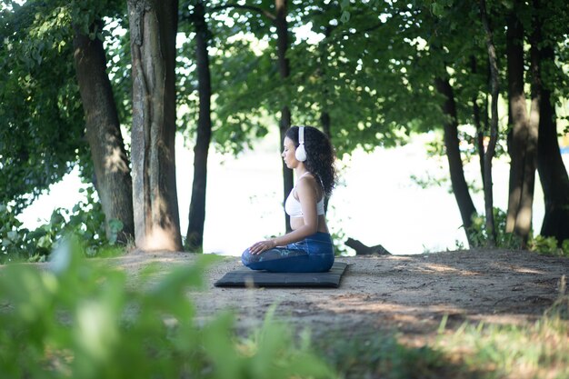 Mulher esportiva com fones de ouvido meditando em posição de lótus