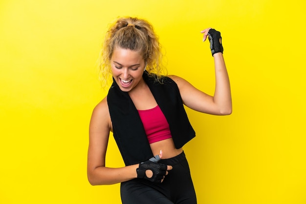 Foto mulher esportiva com toalha isolada em fundo amarelo, fazendo gesto de guitarra