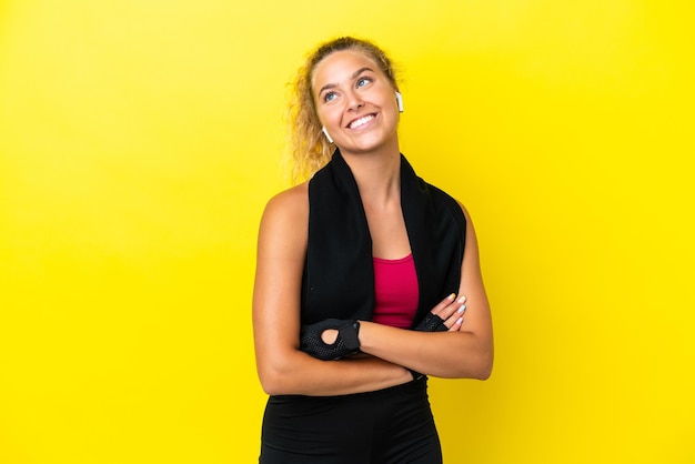 Mulher esportiva com toalha isolada em fundo amarelo olhando para cima enquanto sorria