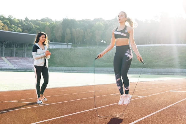 Mulher esportiva com uma boa figura pula corda na pista de esportes do estádio atlética mulher