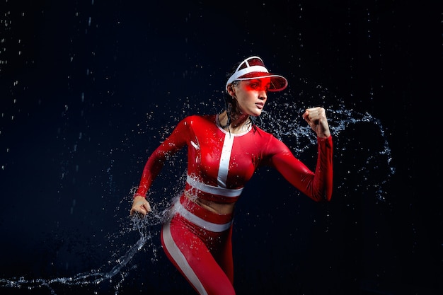 Mulher esportiva correndo sob respingos de água