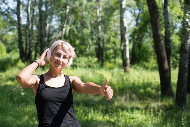 Mulher esportiva está segurando seus fones de ouvido e sorrindo conceito de estilo de vida esportivo