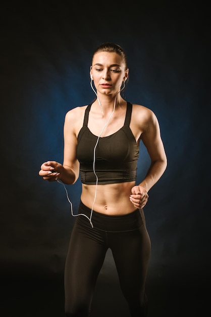 Mulher esportiva magra fazendo exercícios no fundo preto do estúdio