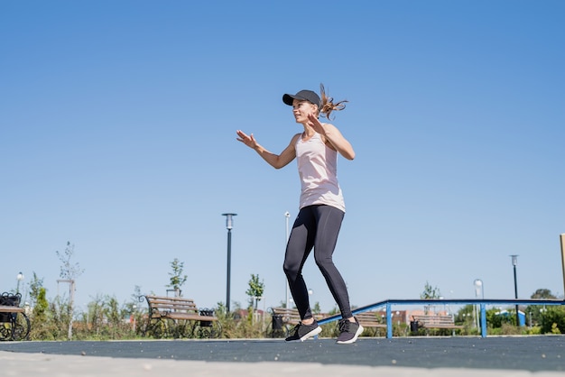 Mulher esportiva malhando na quadra de esportes em um dia ensolarado de verão