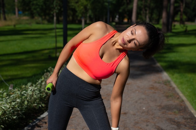 Mulher esportiva se alongando após se exercitar em uma corrida no belo parque