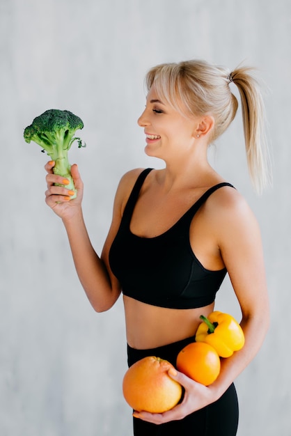 Foto mulher esportiva segurando frutas e legumes frescos nas mãos conceito de alimentação saudável