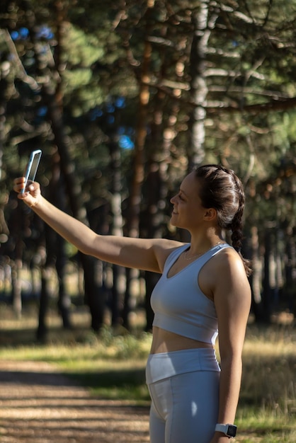 Foto mulher esportiva tirando uma selfie na natureza, natureza de fundo horizontal