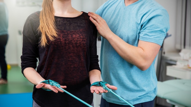 Mulher esportiva usando blusa preta e fazendo exercícios com faixas de resistência