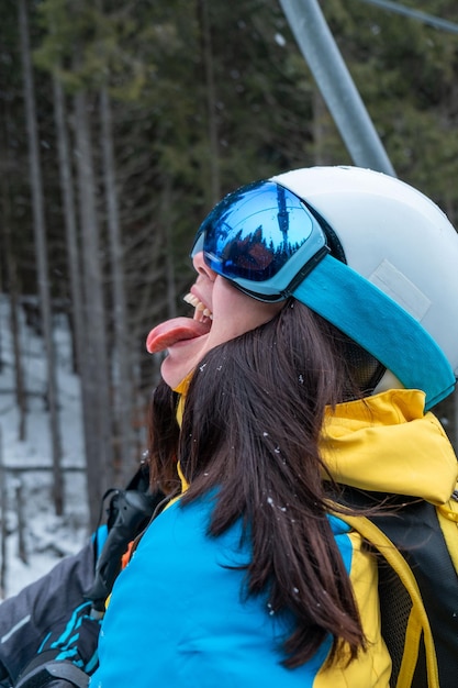 Mulher esquiadora com a língua de fora pegando neve de perto
