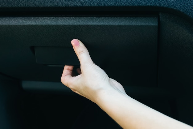 Mulher está abrindo o porta-luvas no carro.