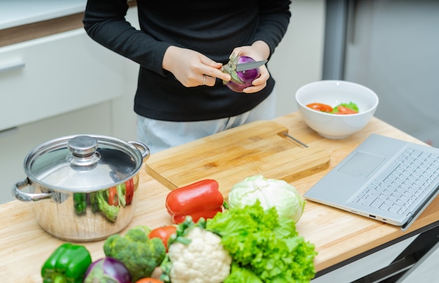 Mulher está aprendendo a cozinhar sozinha em casa, curso de culinária online