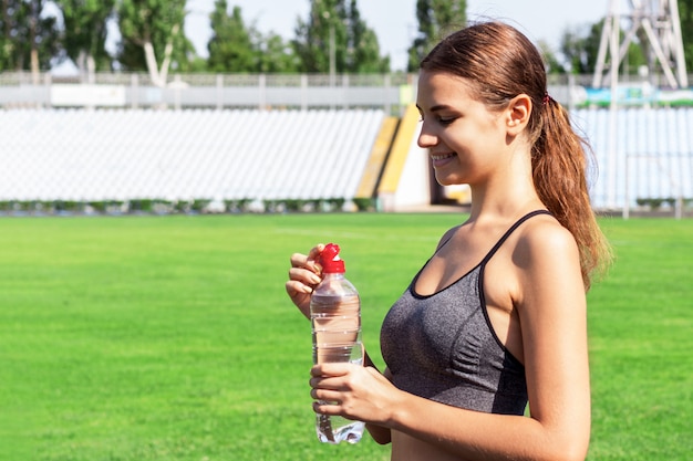 Mulher está bebendo água no estádio