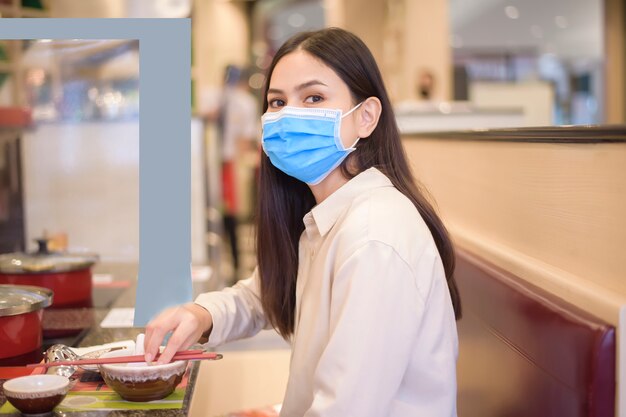 Mulher está comendo em restaurante com protocolo de distanciamento social enquanto cidade bloqueada devido a pandemia de coronavírus