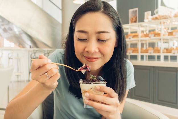 Mulher está comendo o bolo no café da padaria.