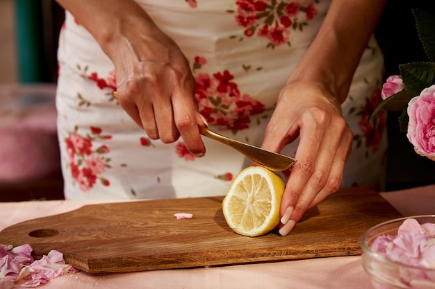 Mulher está cortando limão para chá pétalas de rosas Geléia de chá natural caseira estética preparando com açúcar limão e chá pétalas de rosa Receita saudável Fotografia de estilo de vida