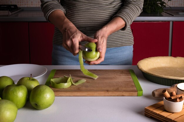 Mulher está descascando maçãs para preparar torta de maçã na cozinha Mãos femininas autênticas descascam uma maçã com uma faca Cozinhar torta de maçã processo de receita passo a passo preparação de Ação de Graças padaria de outono