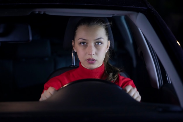 Mulher está dirigindo carro à noite