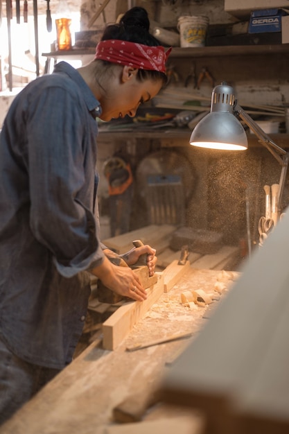 Mulher está envolvida no processamento de madeira na oficina. conceito feito à mão. estilo de vida dos artesãos