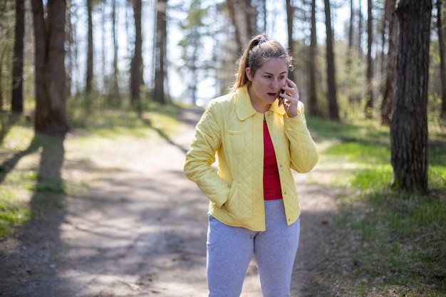 Mulher está falando emocionalmente ao telefone na floresta. Conceito de comunicação celular 5g