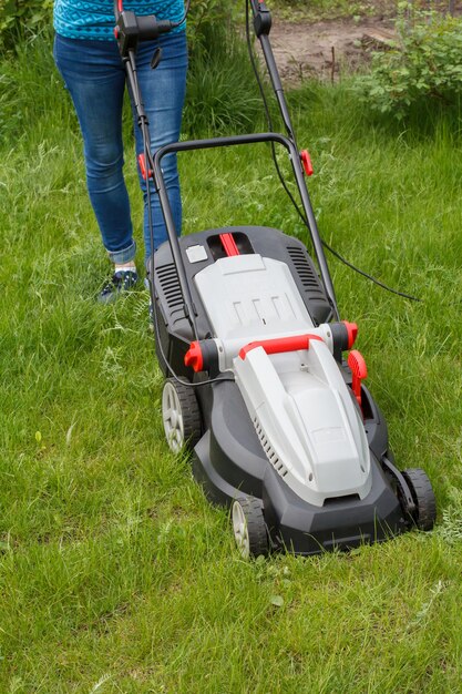 Mulher está operando com cortador de grama no jardim.