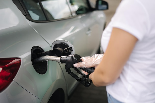 Mulher está reabastecendo no posto de gasolina, mão feminina, enchendo gasolina benzina em um carro usando um combustível