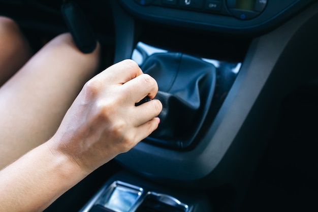 Foto mulher está segurando a caixa de câmbio manual no carro. a garota está dirigindo.