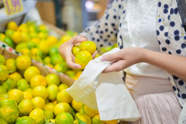 mulher está selecionando frutas em saco de algodão no mercado de alimentos local z