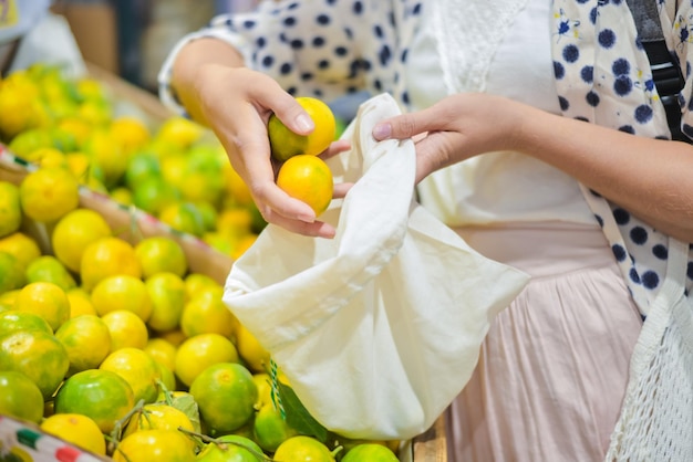 mulher está selecionando frutas em saco de algodão no mercado de alimentos local z