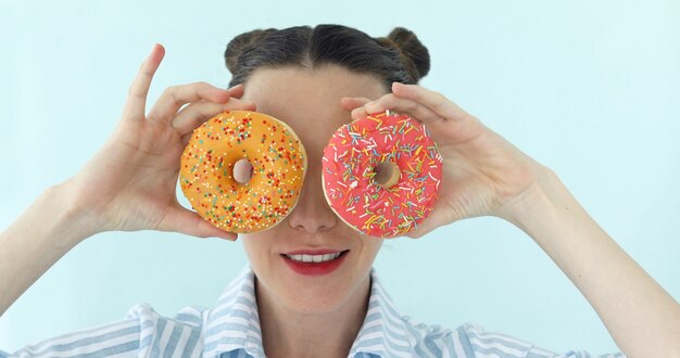 Mulher está tomando donuts e faz óculos de sol