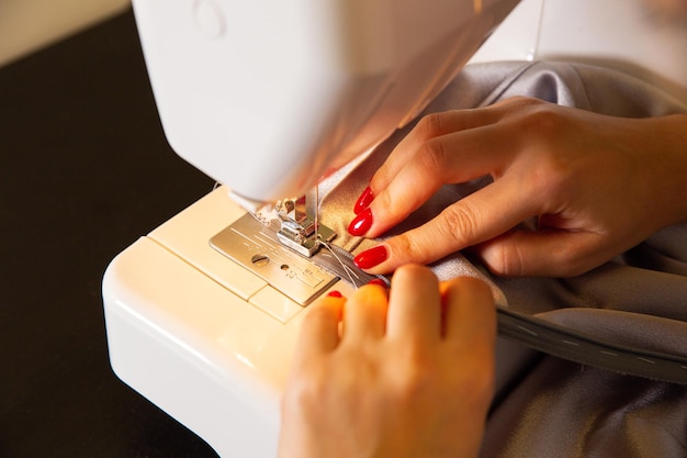 Foto mulher está trabalhando na máquina de costura mãos de meninas com manicure vermelha conceito de moda criação de novo processo de roupas idéias de hobby