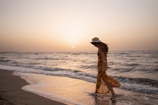 Mulher estilosa de vestido elegante posando perto do mar, horário de verão, fim de semana de viagem relax