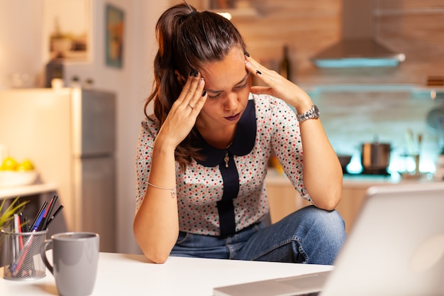 Mulher estressada fazendo hora extra sente fadiga ocular depois do trabalho no computador tarde da noite. Funcionário que usa tecnologia moderna à meia-noite fazendo horas extras para trabalho, negócios, ocupado, carreira, rede, estilo de vida.